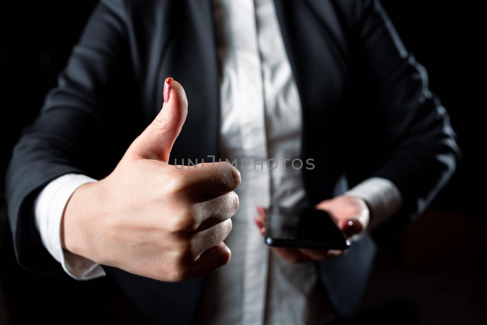 Businesswoman Holding Cellphone And Showing Ok Sign. Woman Having Phone In One Hand And Displaying Thumbs Up With Other. Lady With Tablet Presenting Symbol With One Finger. by nialowwa