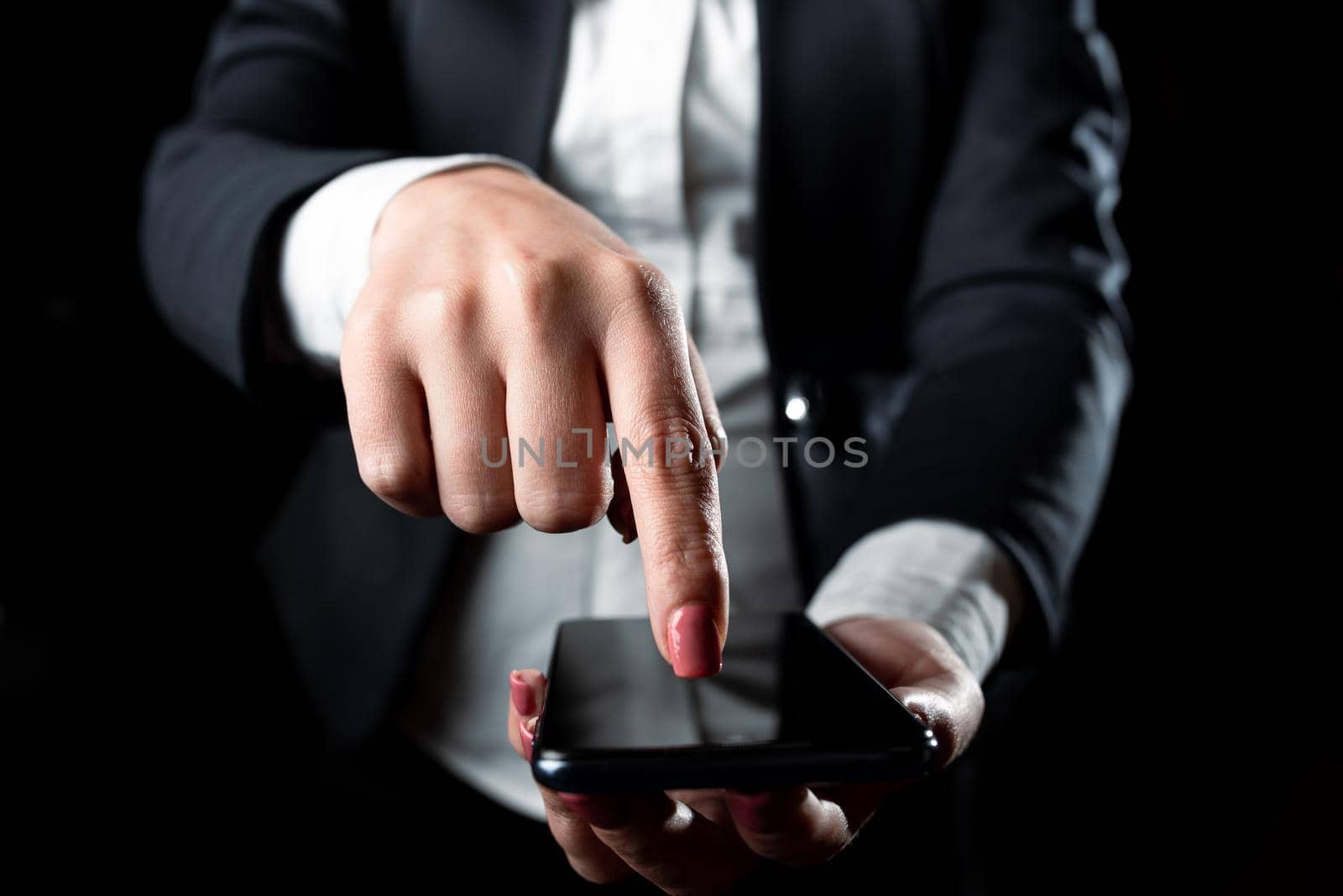 Businesswoman Holding Cellphone And Pointing Important Informations With One Finger. Woman Having Phone And Showing Recent Updates. Executive Displaying Late Achievements. by nialowwa