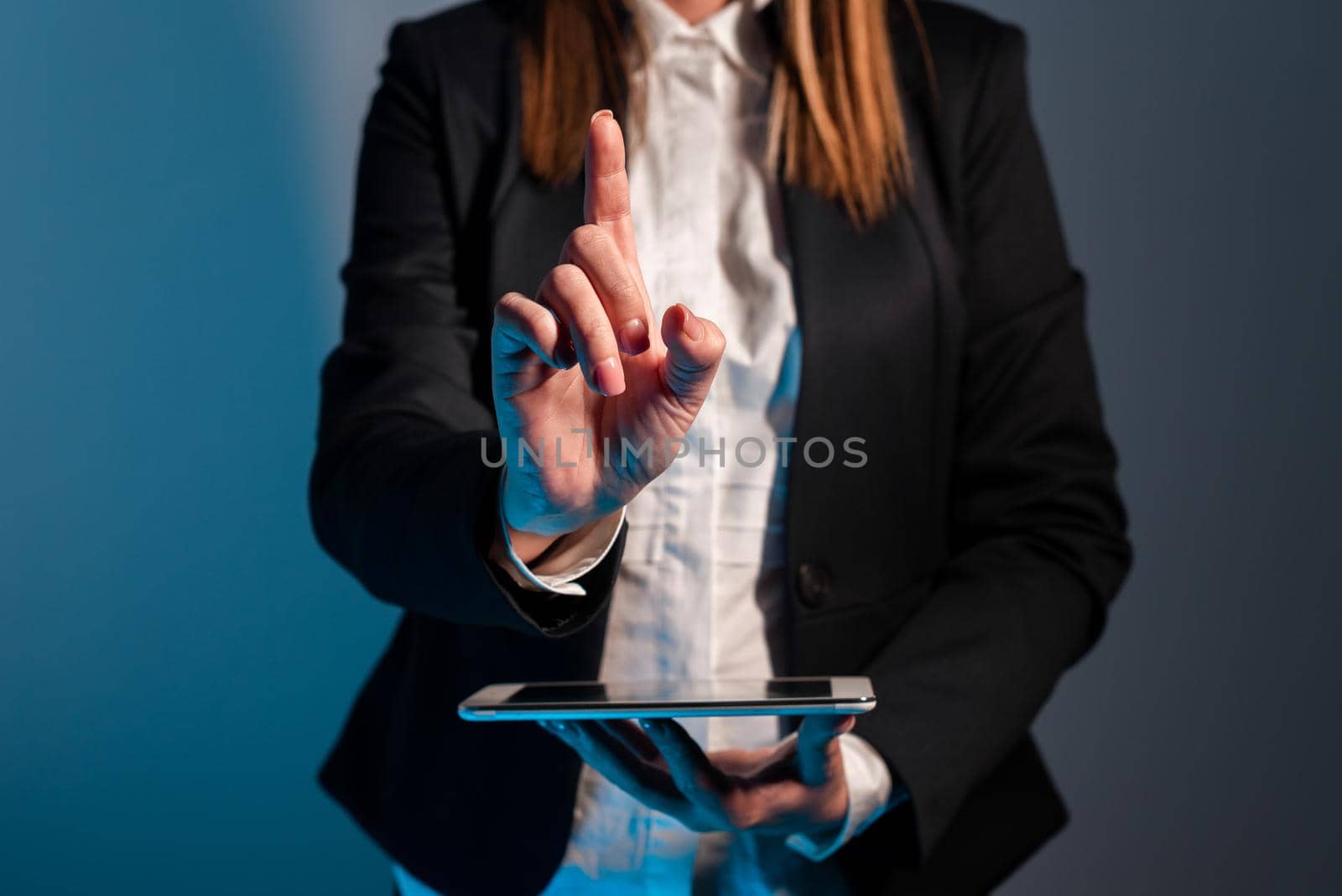 Businesswoman Holding Phone And Pointing With One Finger On Important Message On Desk With Lap Top. Executive In Suit Presenting Crutial Informations. by nialowwa