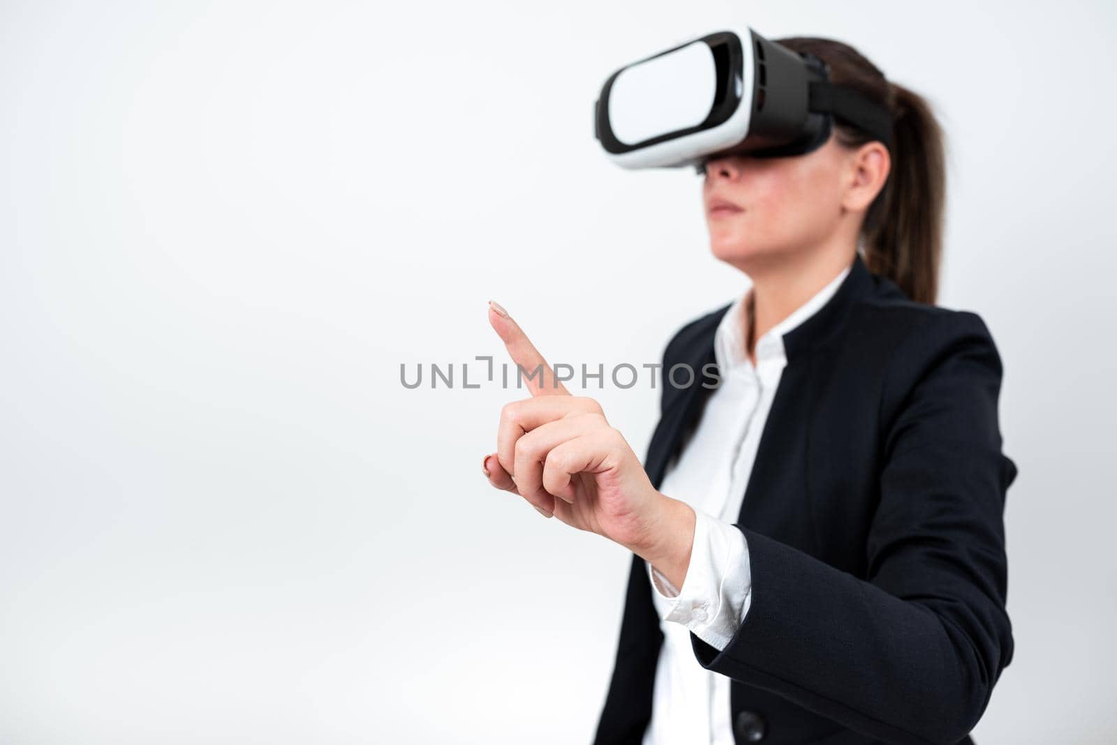 Woman Wearing Vr Glasses And Pointing On Important Messages With One Finger. Businesswoman Having Virtual Reality Eyeglasses And Showing Crutial Informations. by nialowwa