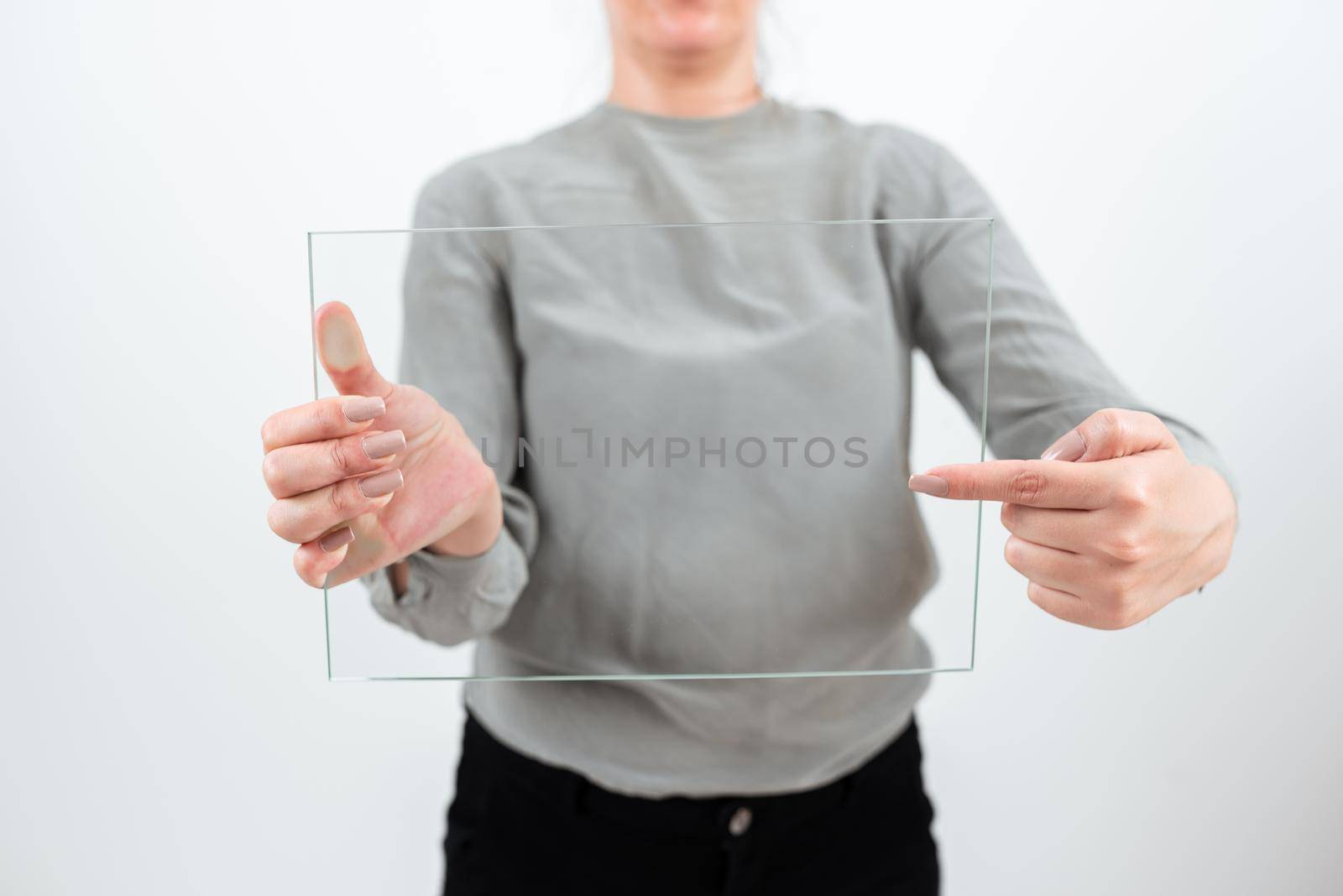 Female Professional Holding And Pointing At Transparent Glass While Displaying Data. Woman Wearing Smart Casual Showing Banner And Promoting The Business For Progress. by nialowwa