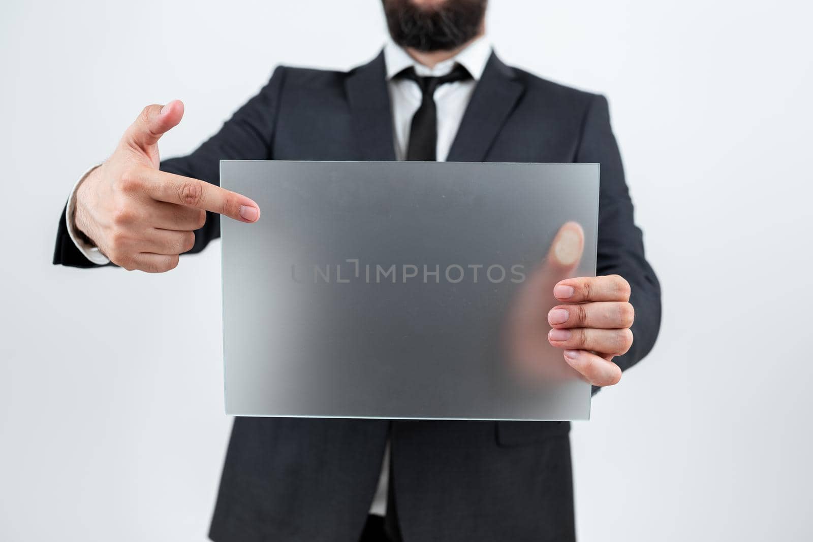 Professional Adult Holding And Pointing At Placard And Presenting Important Information. Businessman Wearing Suit Showing Rectangular Blank Board For Business Advertisement. by nialowwa
