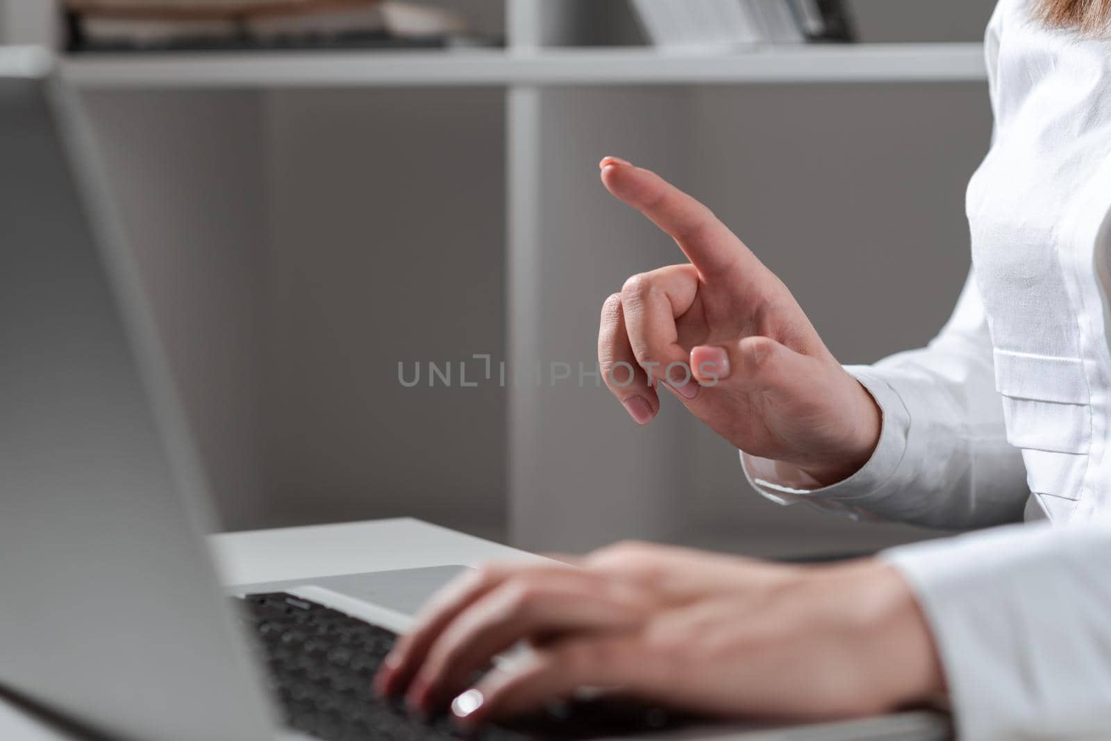 Businesswoman Typing Recent Updates On Lap Top Keyboard On Desk And Pointing Important Ideas With One Finger. Woman In Office Writing Late Messages On Computer. by nialowwa