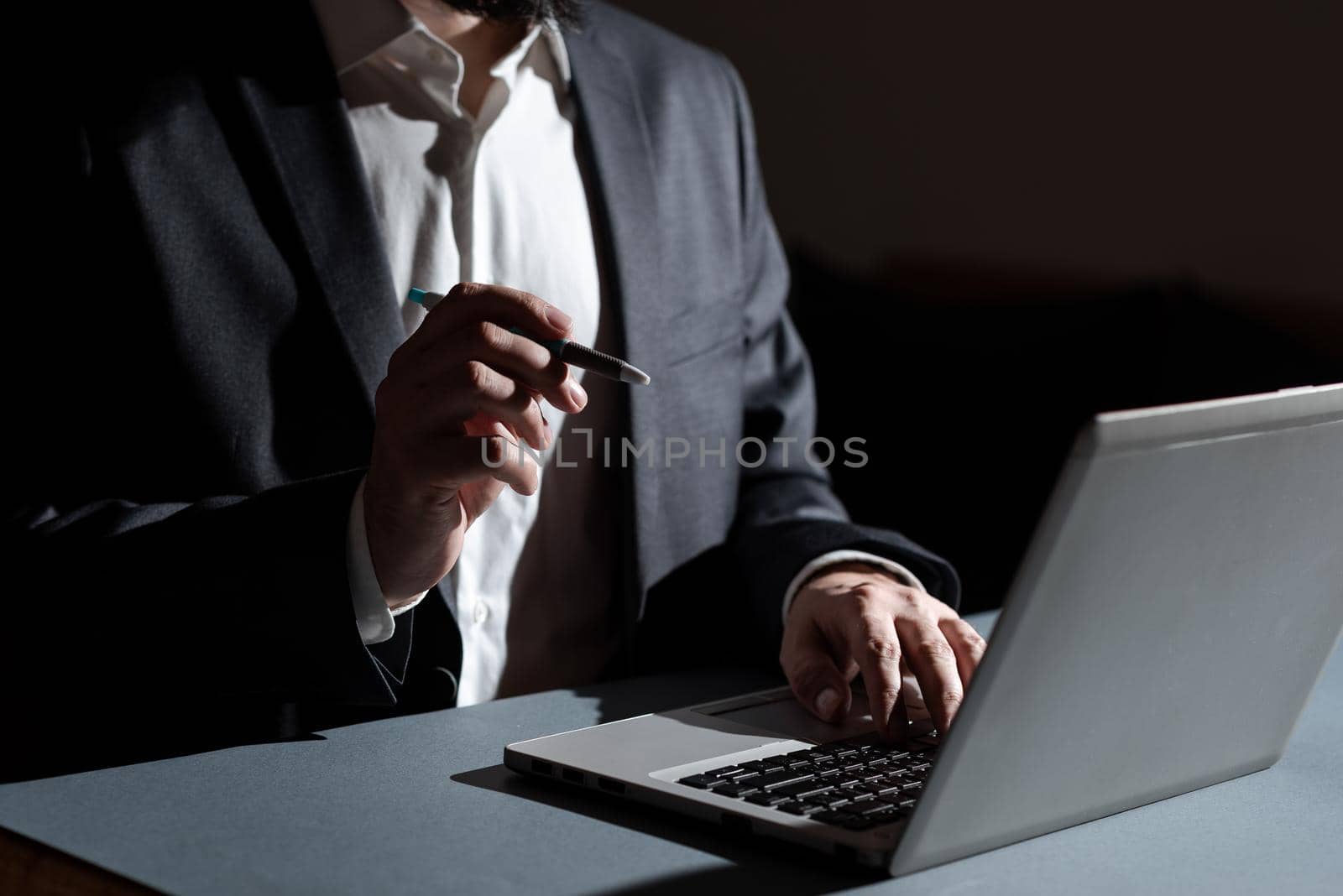 Businessman Typing Important Concept Into Lap Top And Pointing New Idea With Pen. Man In Suit Writing Crutial Messages On Computer Keyboard. Executive Presenting Late Data. by nialowwa