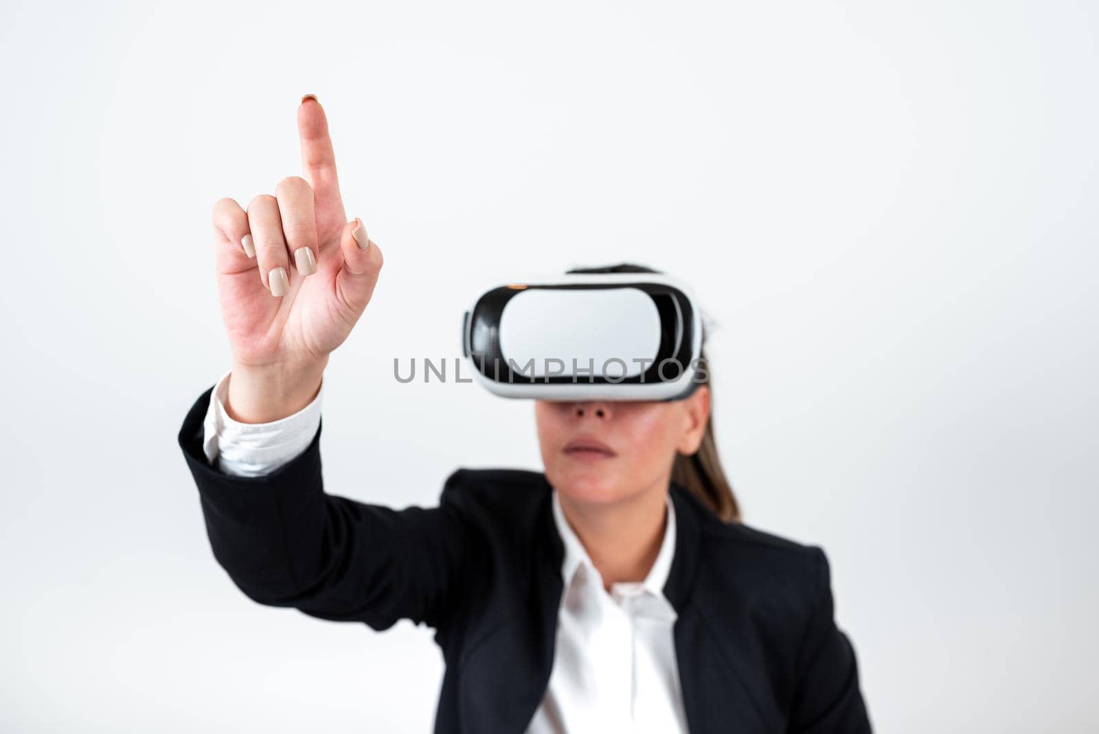 Woman Wearing Vr Glasses And Pointing On Important Messages With One Finger. Businesswoman Having Virtual Reality Eyeglasses And Showing Crutial Informations. by nialowwa