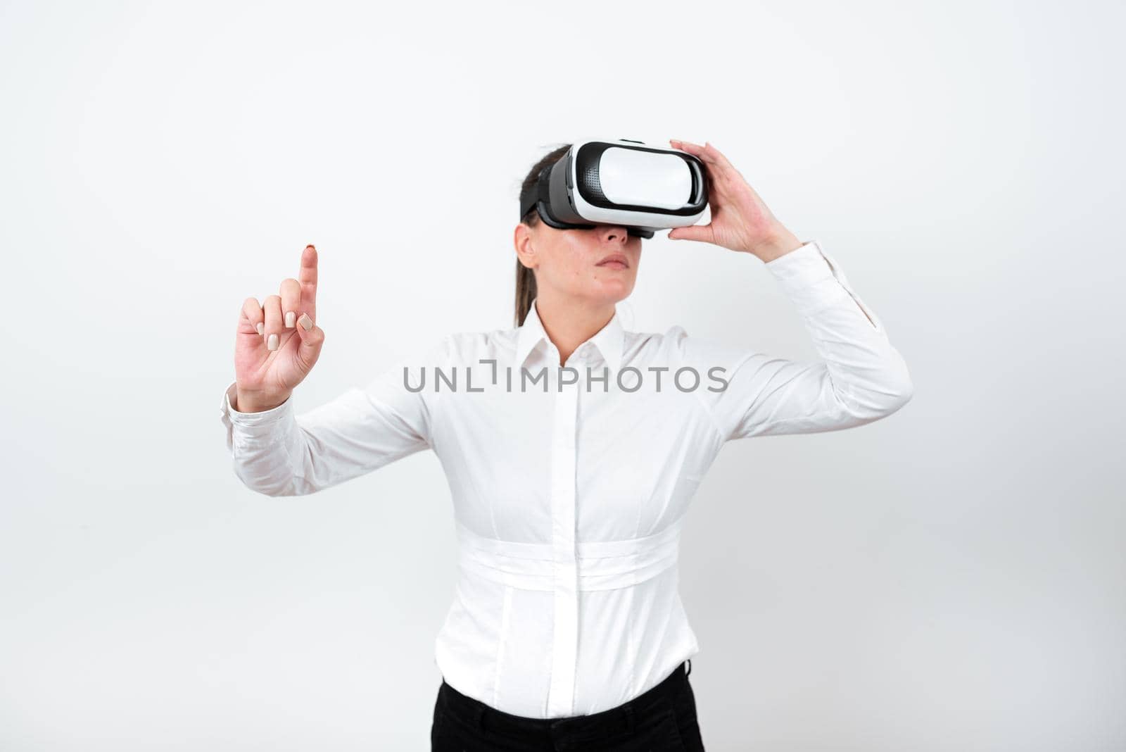 Woman Wearing Vr Glasses And Pointing On Important Messages With One Finger. Businesswoman Having Virtual Reality Eyeglasses And Showing Crutial Informations. by nialowwa