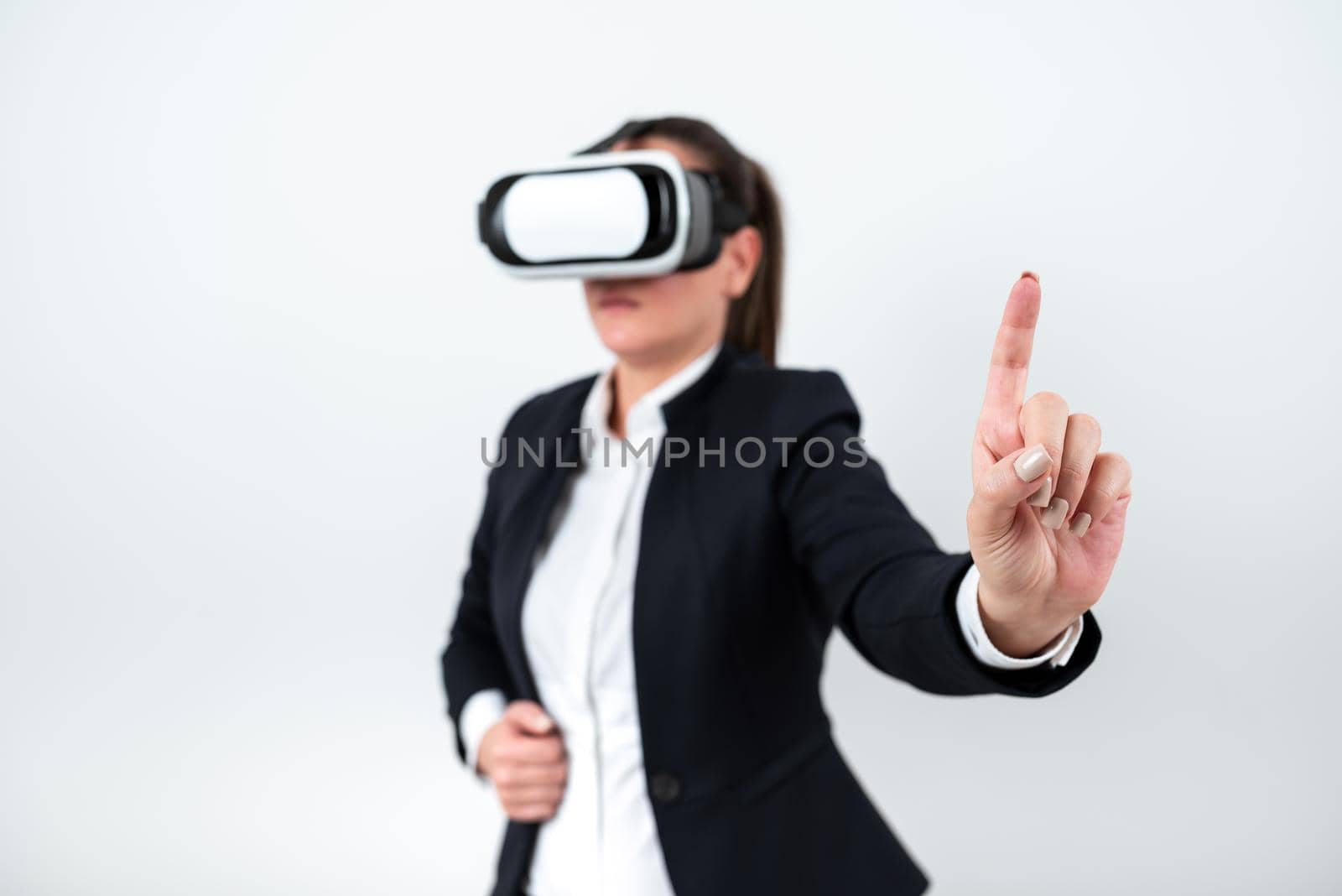 Woman Wearing Vr Glasses And Pointing On Important Messages With One Finger. Businesswoman Having Virtual Reality Eyeglasses And Showing Crutial Informations. by nialowwa