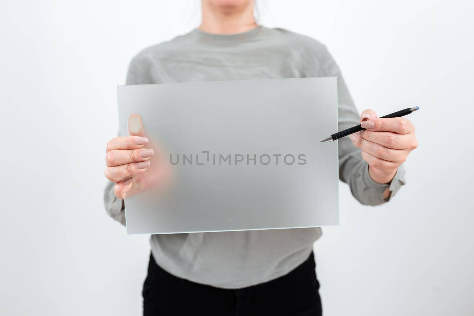 Female Worker Holding Pen And Blank Placard Displaying Important Information. Woman Wearing Smart Casual Showing Banner While Advertising The Business For Company Growth. by nialowwa