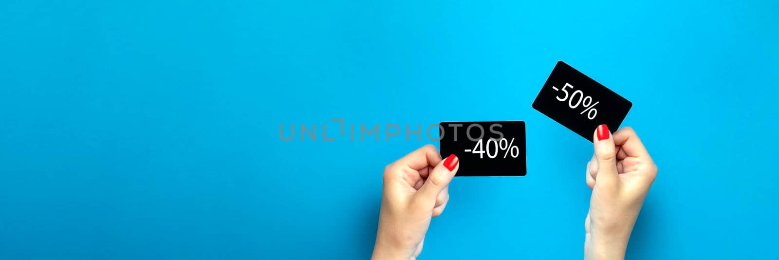 Discount card in hand. Discount on purchases 40, 50 , percent. A woman is holding a black discount card on a blue background. Banner or poster for advertising or print. Place for text by SERSOL