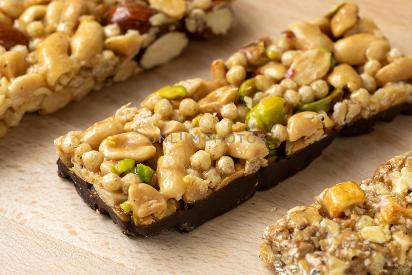 Cereal superfood energy bars with almond nuts, dry fruits, raisins chocolate on the wood table by xtrekx