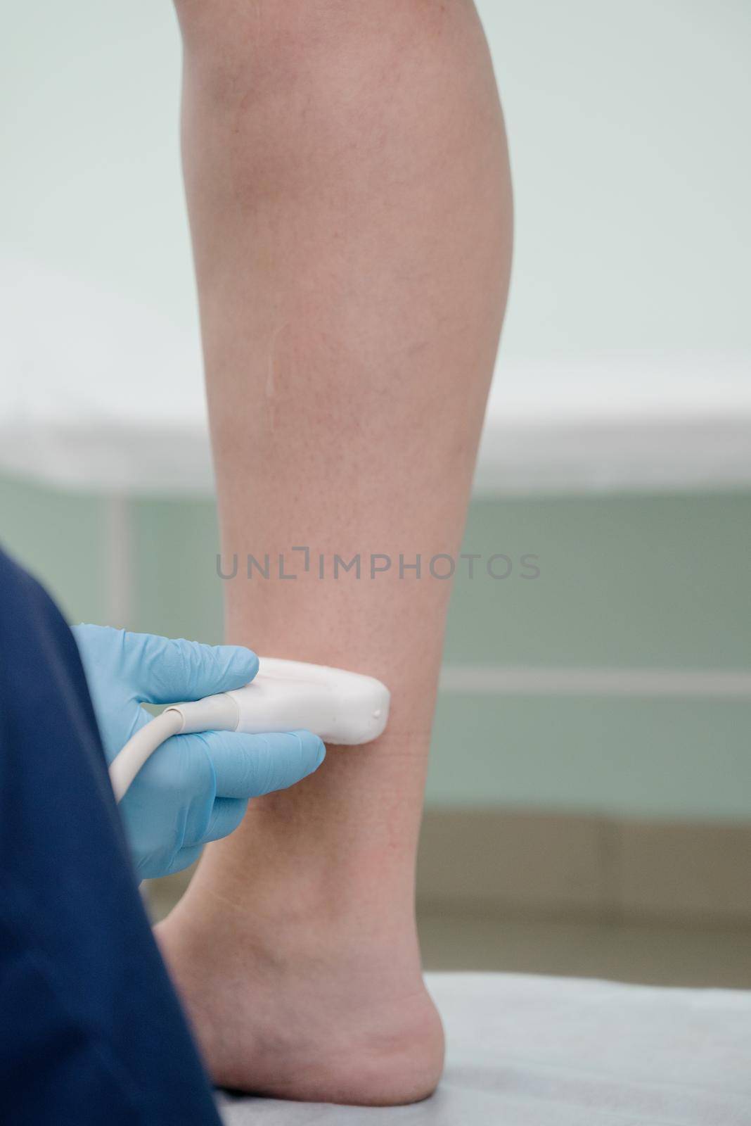 An orthopedic surgeon performs an ultrasound examination of the patient's leg veins in his office.Doctor ultrasound knee test. Scan medical equipment. Varicose ankle exam tool.