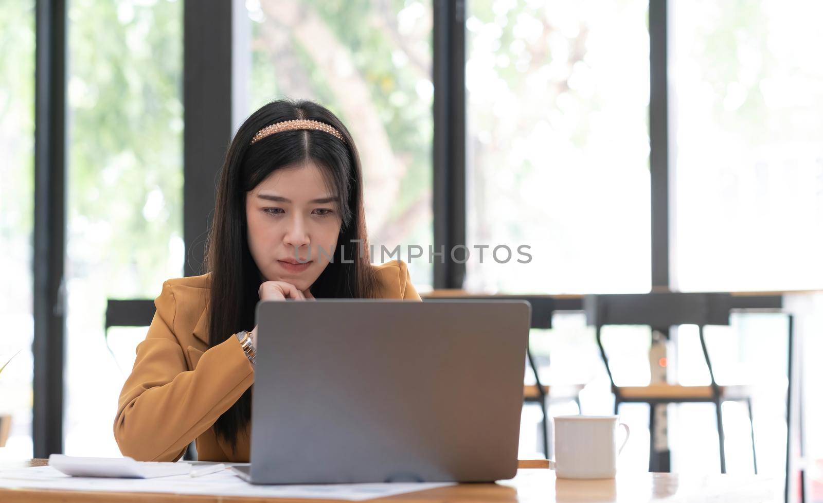 Young Asian woman working at office using a laptop computer on a table..