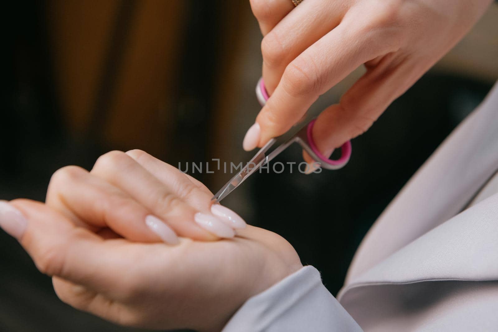 Woman is making manicure at home cutting cuticle using scissors, hands closeup.beauty salon, manicure applying, cutting the cuticle with scissors