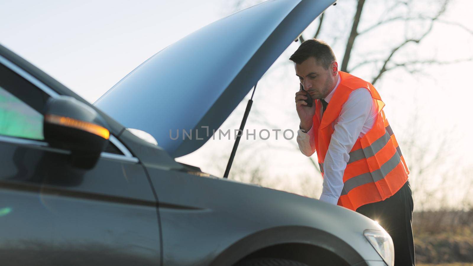 Businessman standing speak on phone near car opened the hood road help repair stress problem emergency insurance auto. Car accident on the road. Emergency stop sign.