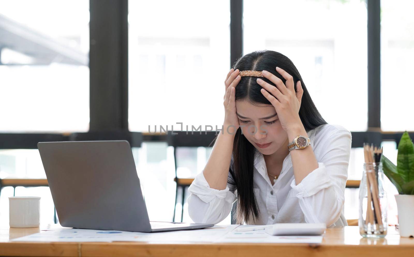 Image of an Asian business woman is stressed, bored, and overthinking from working on a tablet at the office..