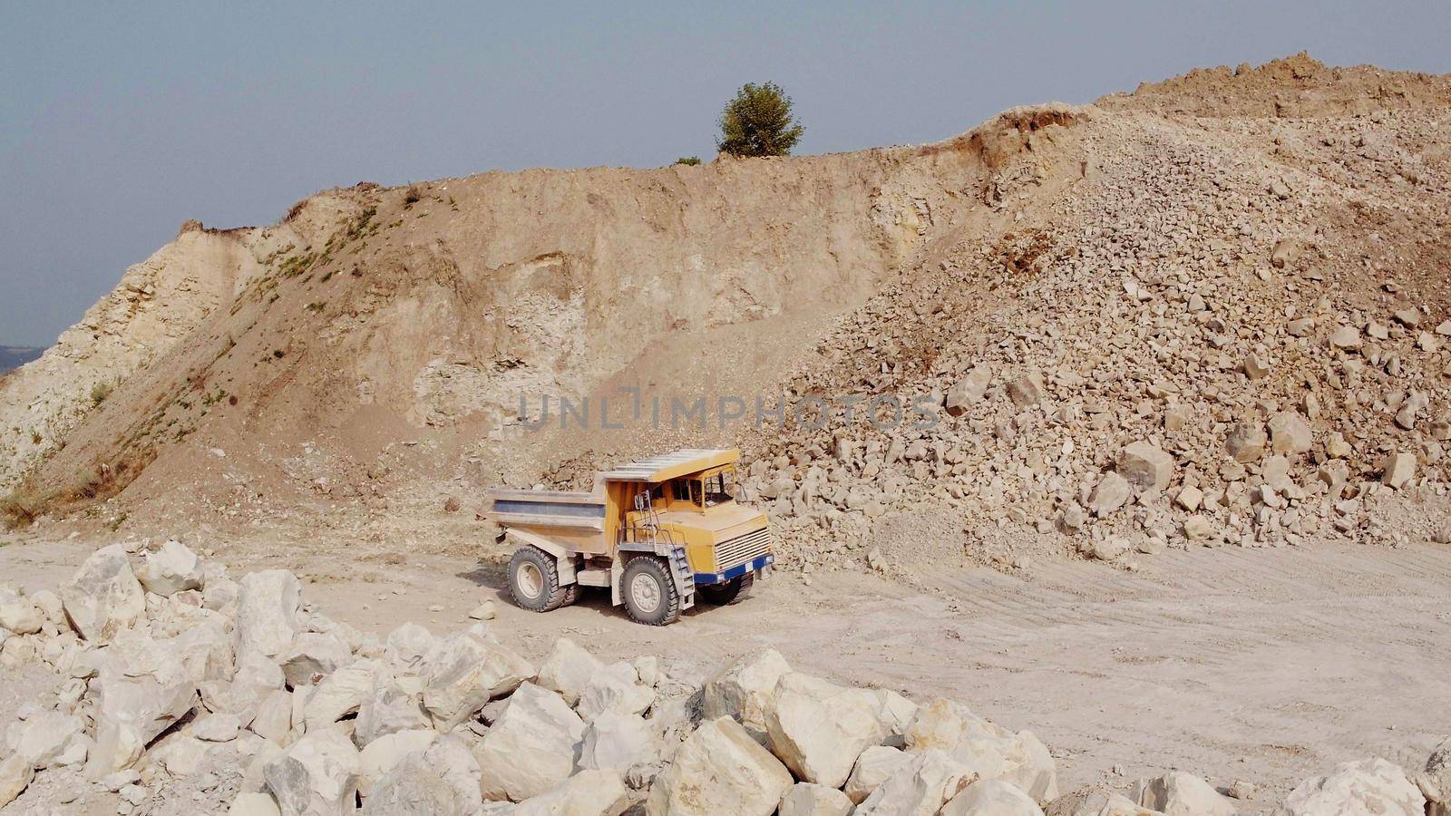 Mining truck is driving an iron ore mine loaded with ore. Open pit mine quarrying extractive industry stripping work. Quarry Dump Truck by uflypro