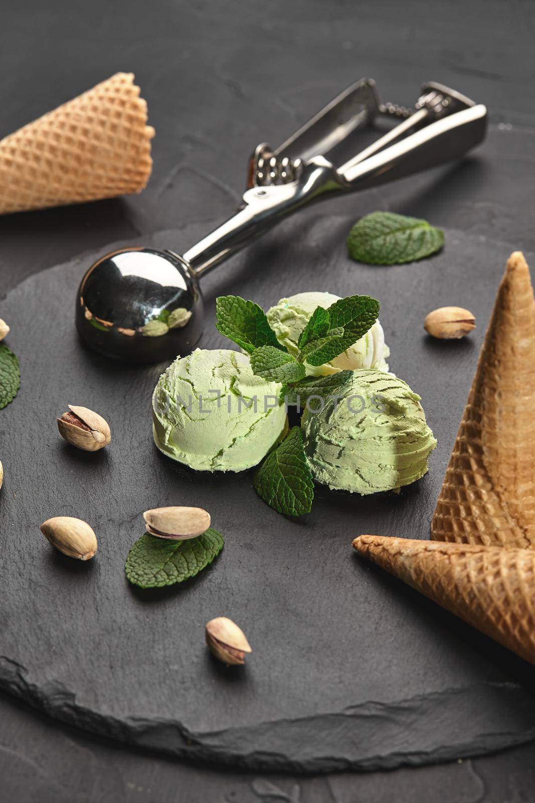 Gourmet pistachio ice cream served on a stone slate over a black background. by nazarovsergey