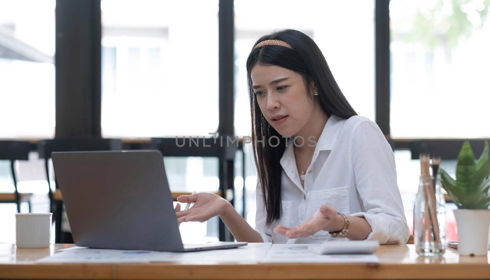 young female working online, using laptop computer at home. woman having remote business conference, sitting at desk with pc by wichayada