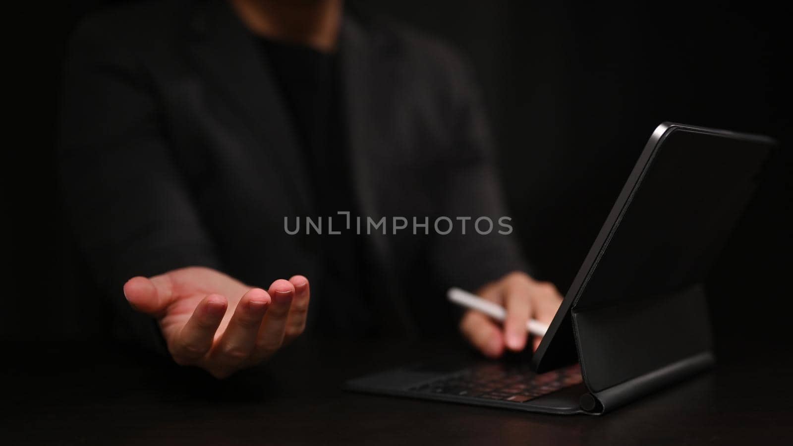 Cropped image of businessman using computer tablet and hand showing or holding something.