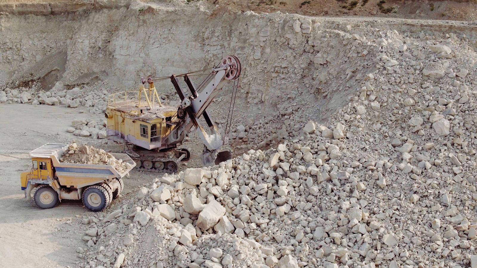 An excavator loads soil into a mining dump truck. Equipment for the extraction of iron ore in a quarry. The process of mining iron ore in a quarry. The smart process in an iron ore quarry.
