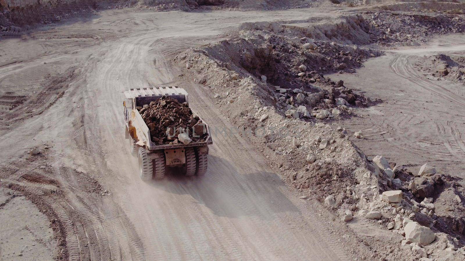 Dump truck loaded with ore and driving through the pit. Big yellow heavy truck in open cast mine mining of coal the overall plan. Open pit anthracite mining, mining truck at work working in quarry by uflypro