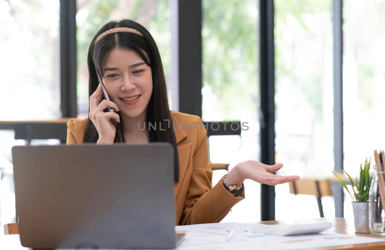 Asian business woman have the joy of talking on the phone, laptop and tablet on the office desk..