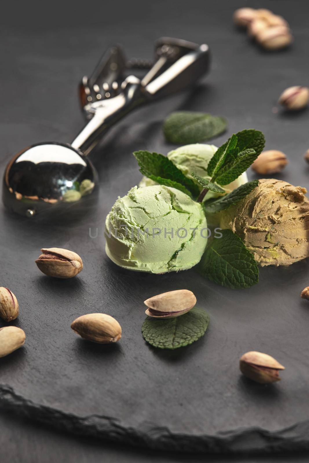 Gourmet chocolate and pistachio ice cream served on a stone slate over a black background. by nazarovsergey