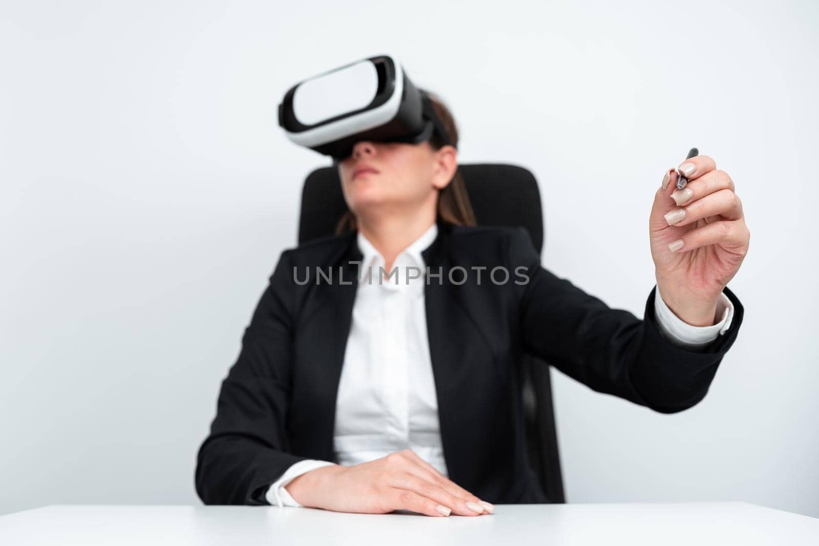 Businesswoman Wearing Virtual Reality Simulator And Holding Pen At Desk.