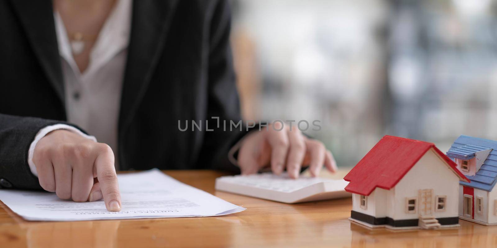 Businesswoman or real estate agent sitting at table with wooden house model and gavel, real estate banner background. by wichayada