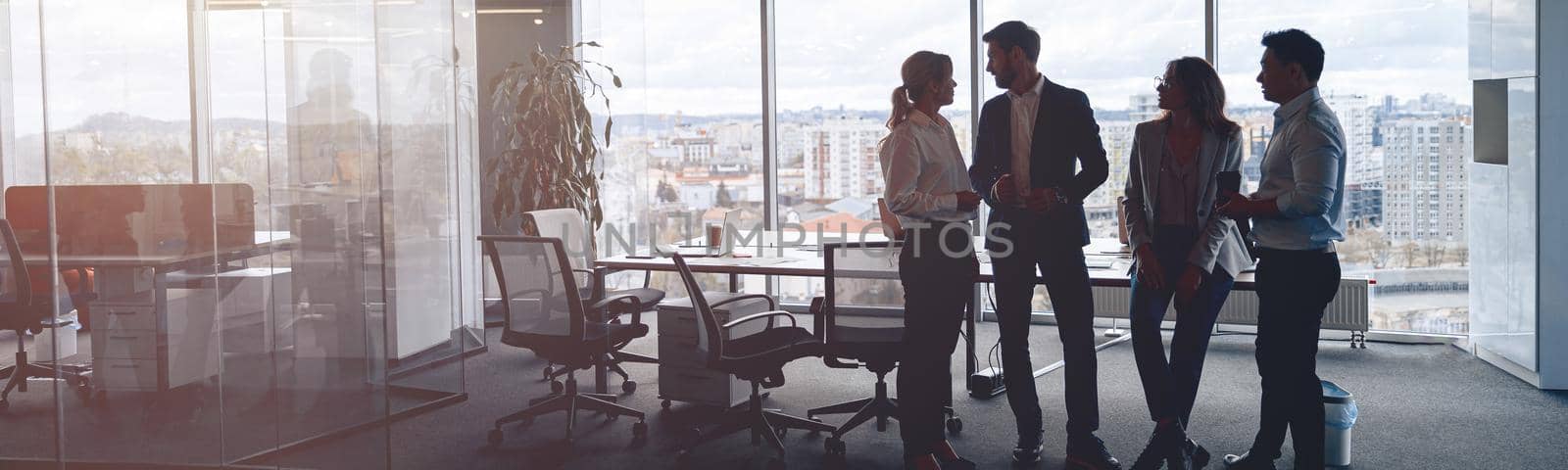 Business team standing against panoramic windows in modern office by Yaroslav_astakhov