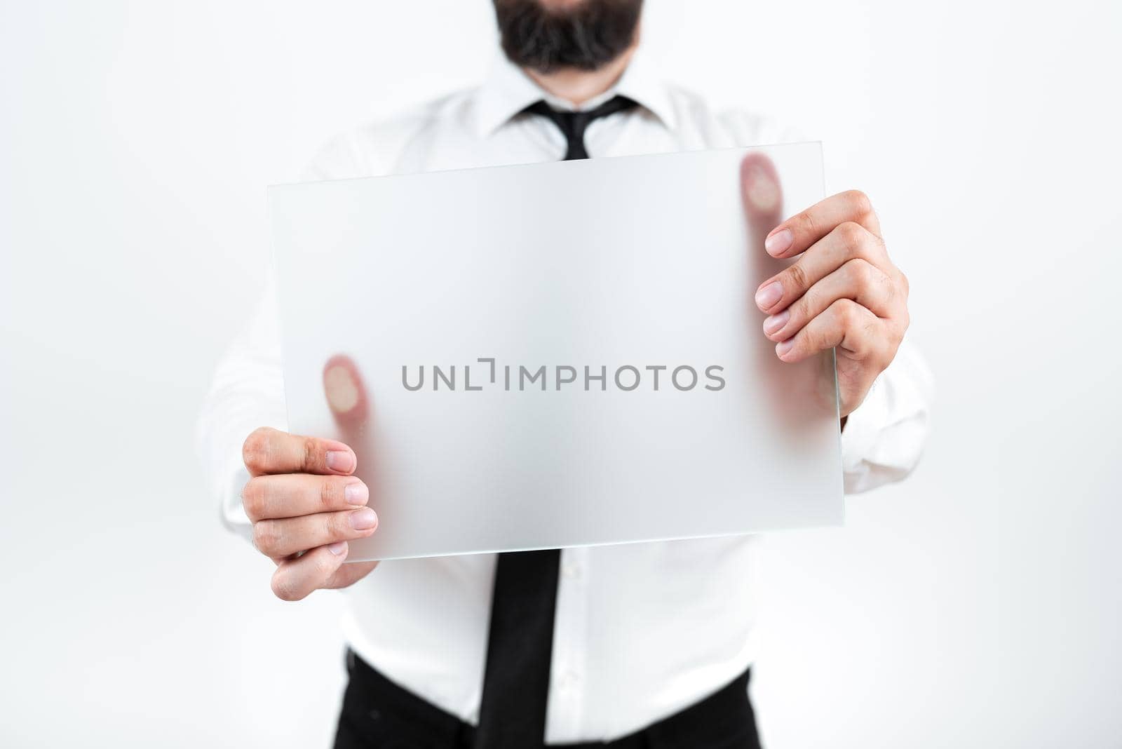 Male Professional Wearing Necktie Holding Blank Placard And Displaying Important Message. Businessman With Paper In Hands Presenting Strategies And Information For Progress. by nialowwa