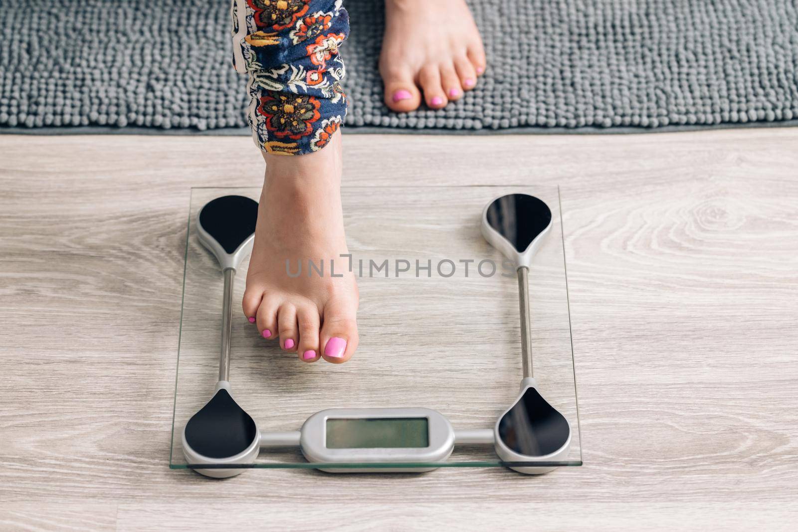 Female checking BMI weight loss. Girl barefoot measuring body fat overweight. Woman on scales measure weight. Girl legs step on bathroom scale. Diet woman feet standing weighing scales on room