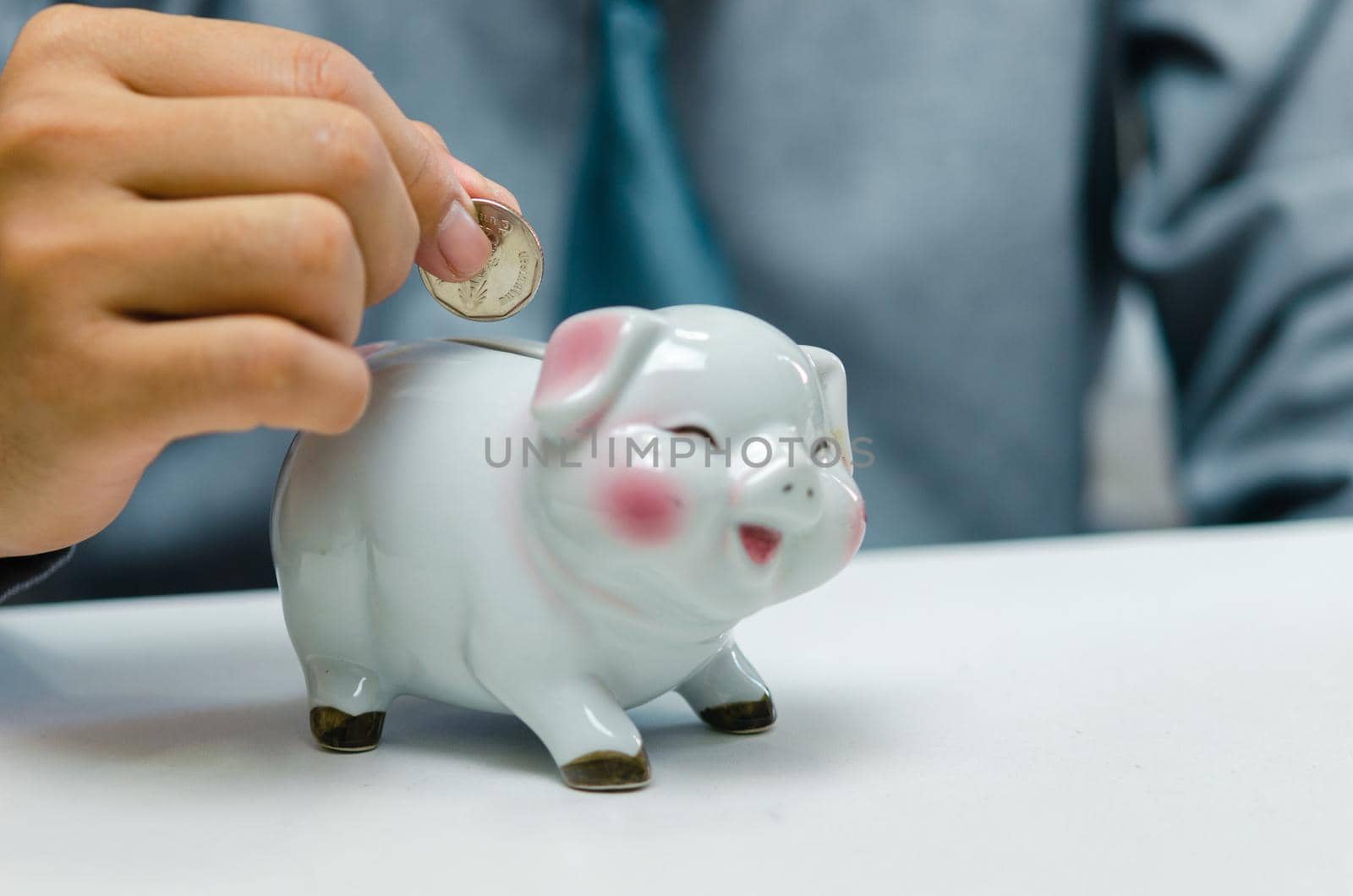 Businessman person hand holding coin money saving piggybank on table.Business finance account investment tax economy insurance and plan retirement concept.