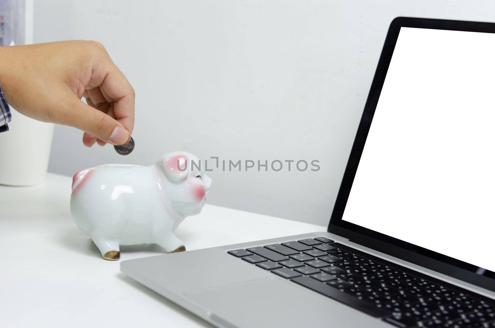 Man hand holding coin at piggy bank finance and computer laptop. business investment saving technology concept.