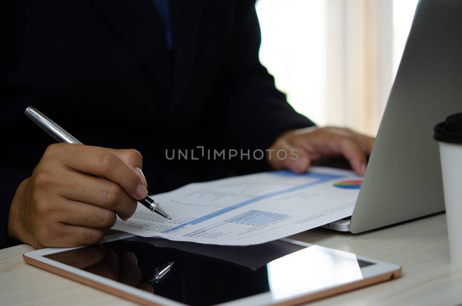 businessman holding pen to work computer graphs and charts data statistical data financial analysis documents. by aoo3771