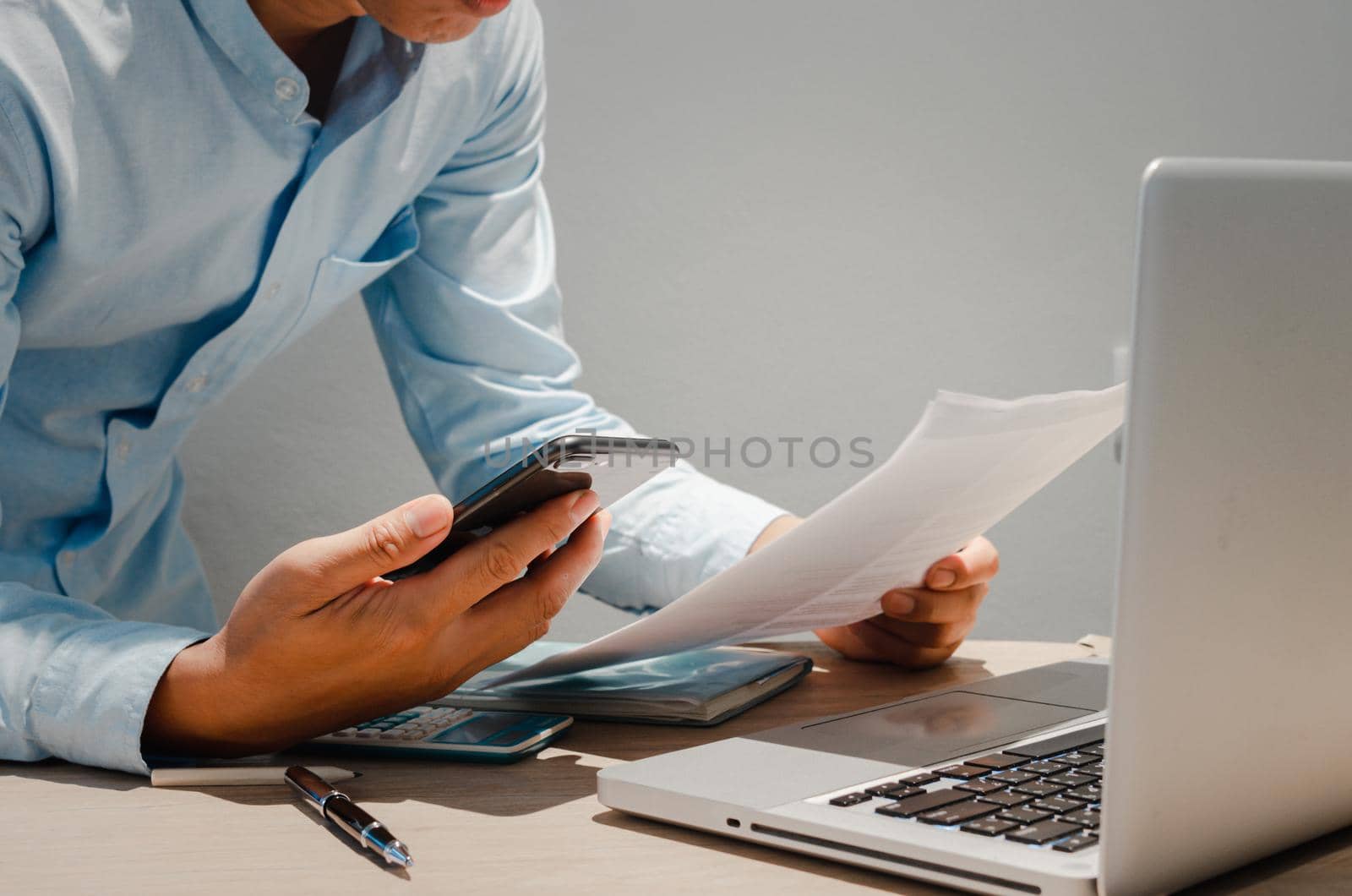 Businessman holding mobile smart phone and paperwork document finance investment and marketing concept with computer laptop on desk. by aoo3771