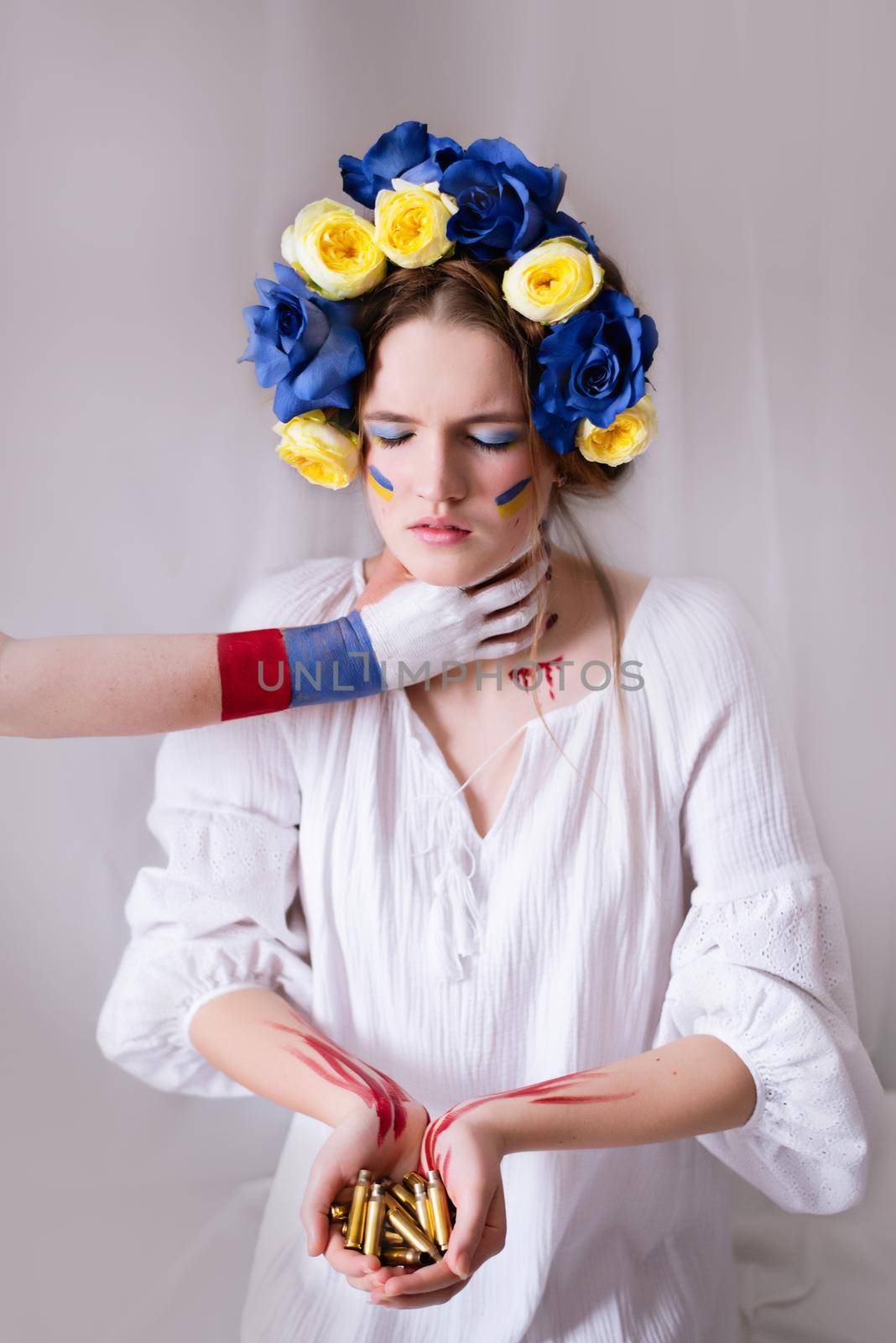 A young Ukrainian woman during the war with a yellow blue wreath of bullets and blood on a white background close-up. Russia attacked Ukraine in 2022