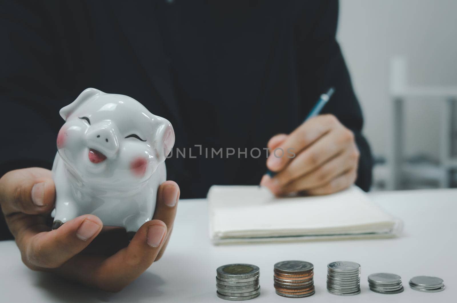 Businessman person hand holding saving piggybank coin money on table.Business finance account investment tax economy insurance and plan retirement concept.