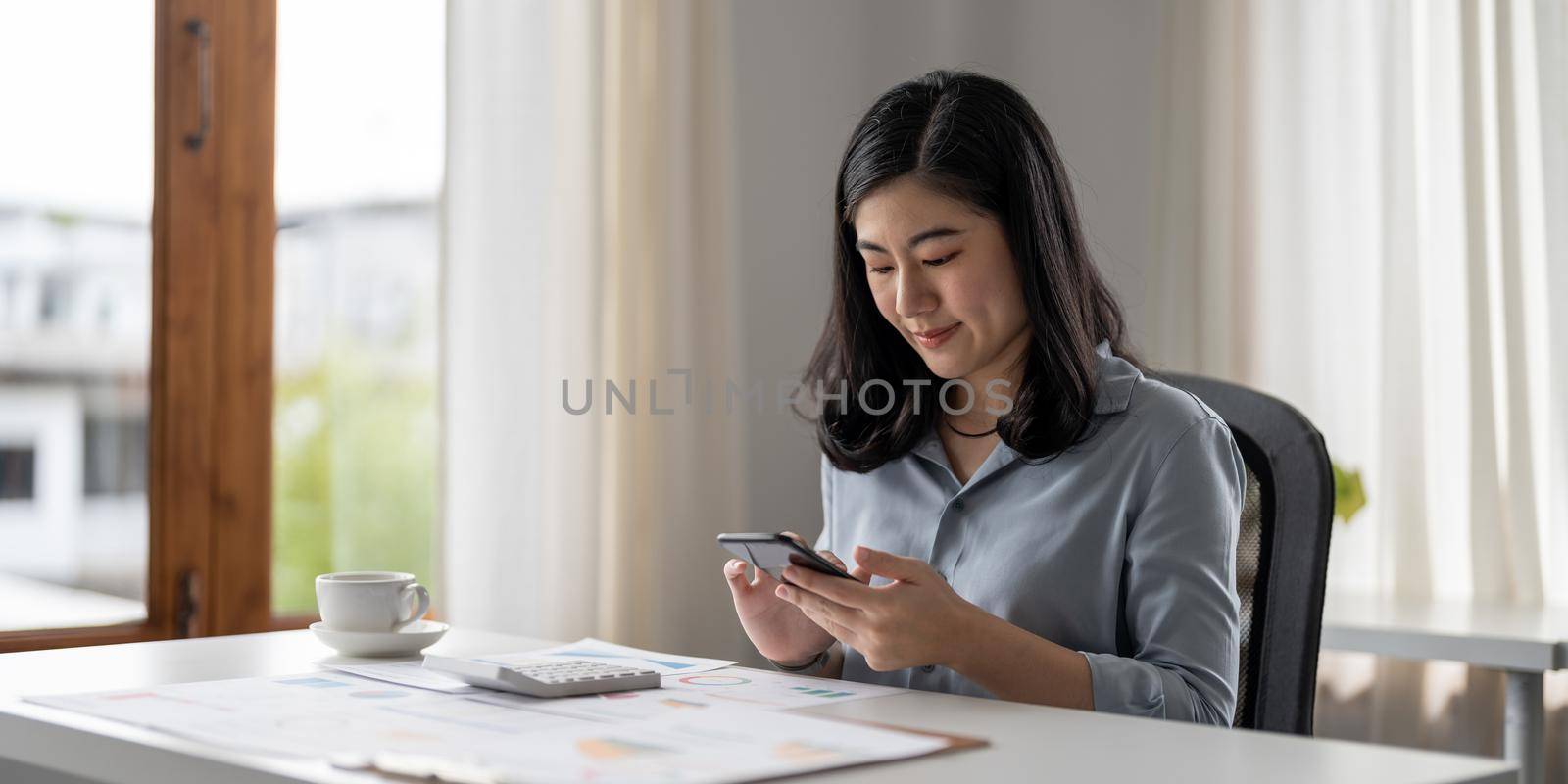 Business asian woman using mobile phone during checking an email or social media on internet. accounting financial concept. by nateemee