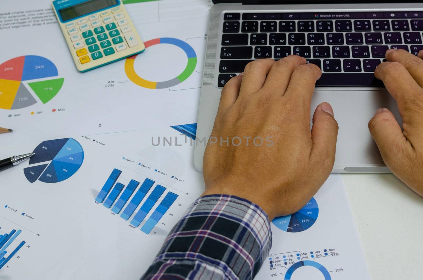 Businessman person hand using keyboard computer laptop with document chart finance and graph report investment at office.Paperwork management analysis marketing and tax economy concept.