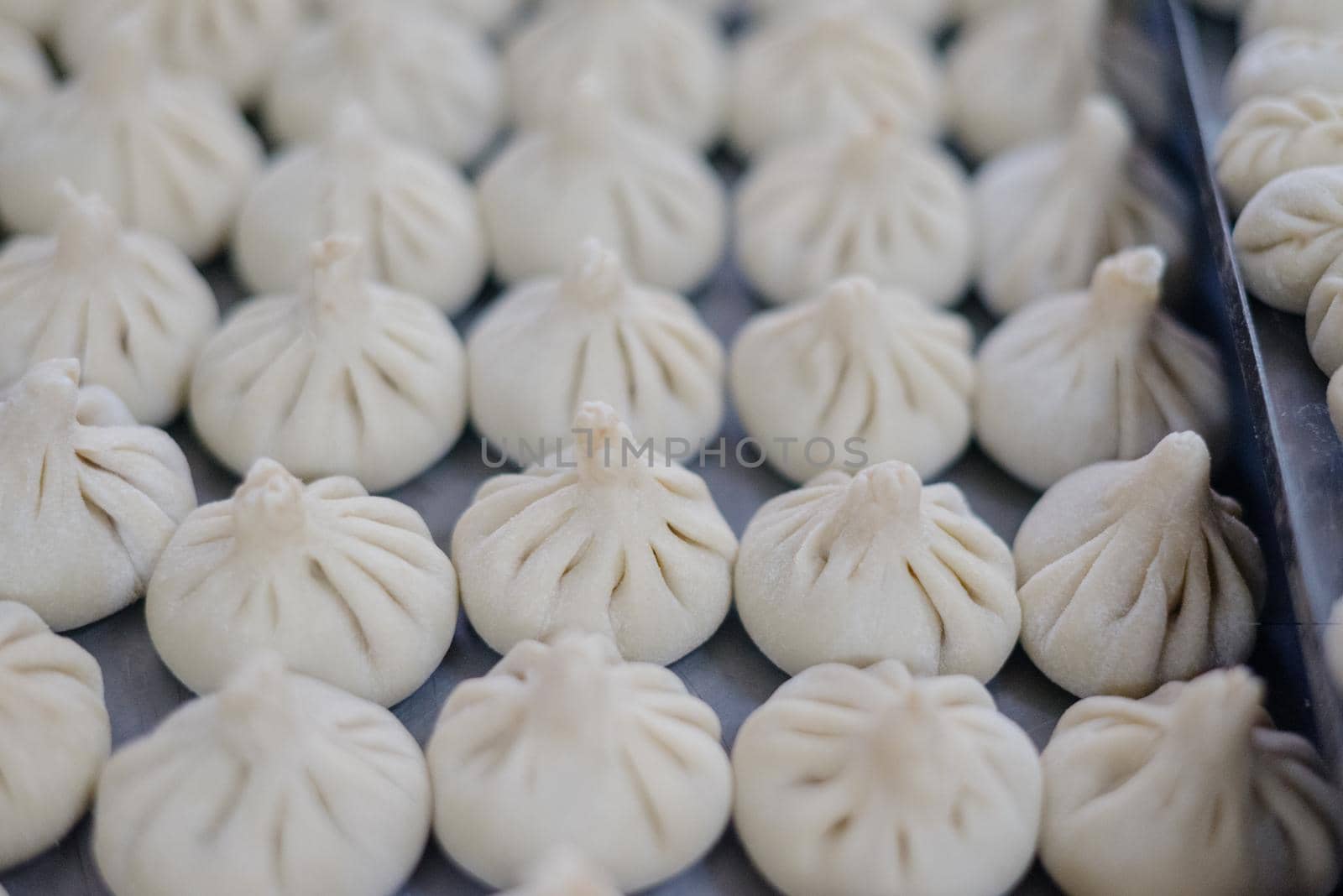 Dumplings with minced meat and dough on table sprinkled with flour. Raw homemade delicious traditional italian ravioli with meat on wooden table.Russian food