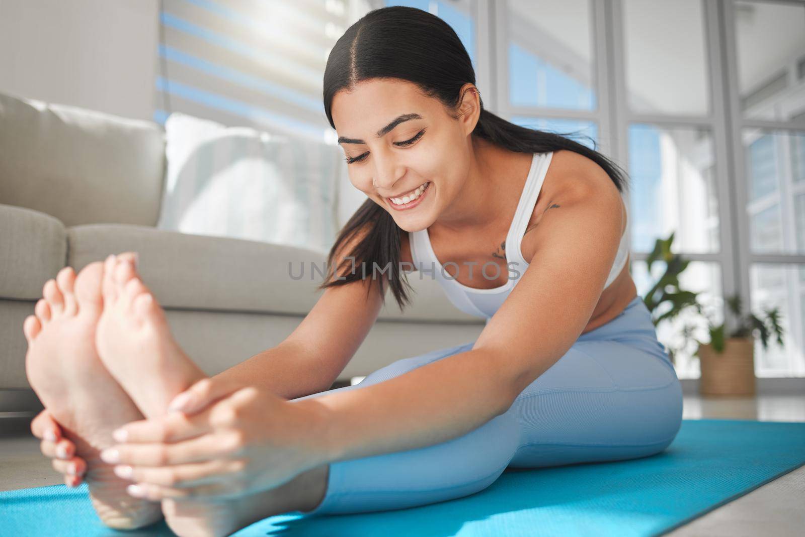 a sporty young woman stretching while exercising at home.