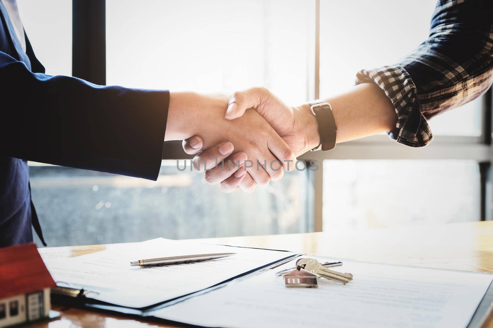 Focus on the congratulatory handshake. The real estate agent agrees to buy the home and hand the keys to the customer at the agent's office. conceptual agreement. by Manastrong