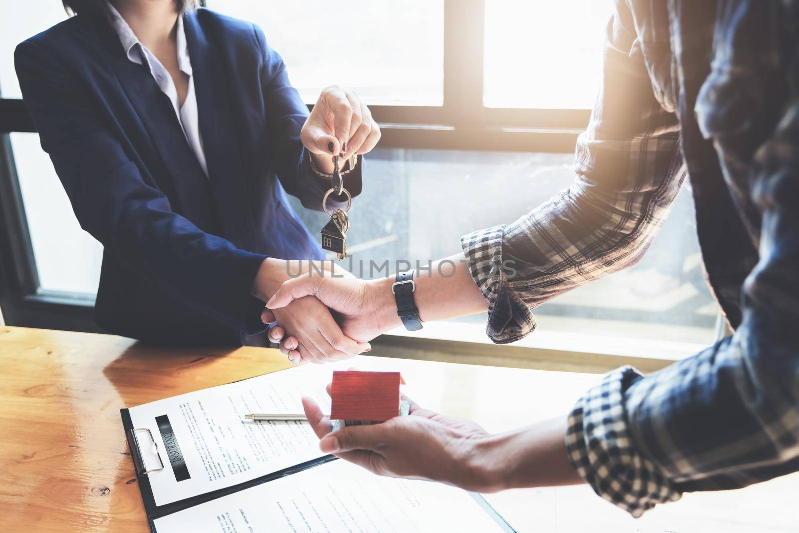 Focus on the congratulatory handshake. The real estate agent agrees to buy the home and hand the keys to the customer at the agent's office. conceptual agreement