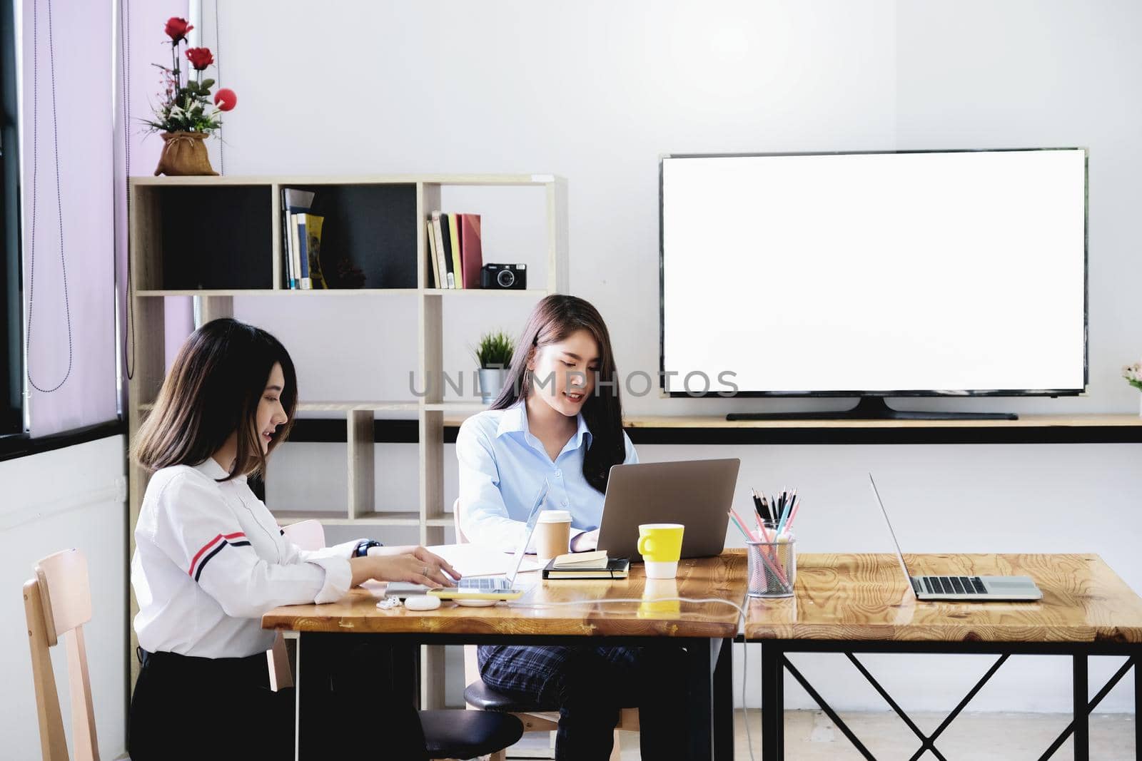 freelance concept, a group of female employees using computers to design work as ordered by customers. by Manastrong