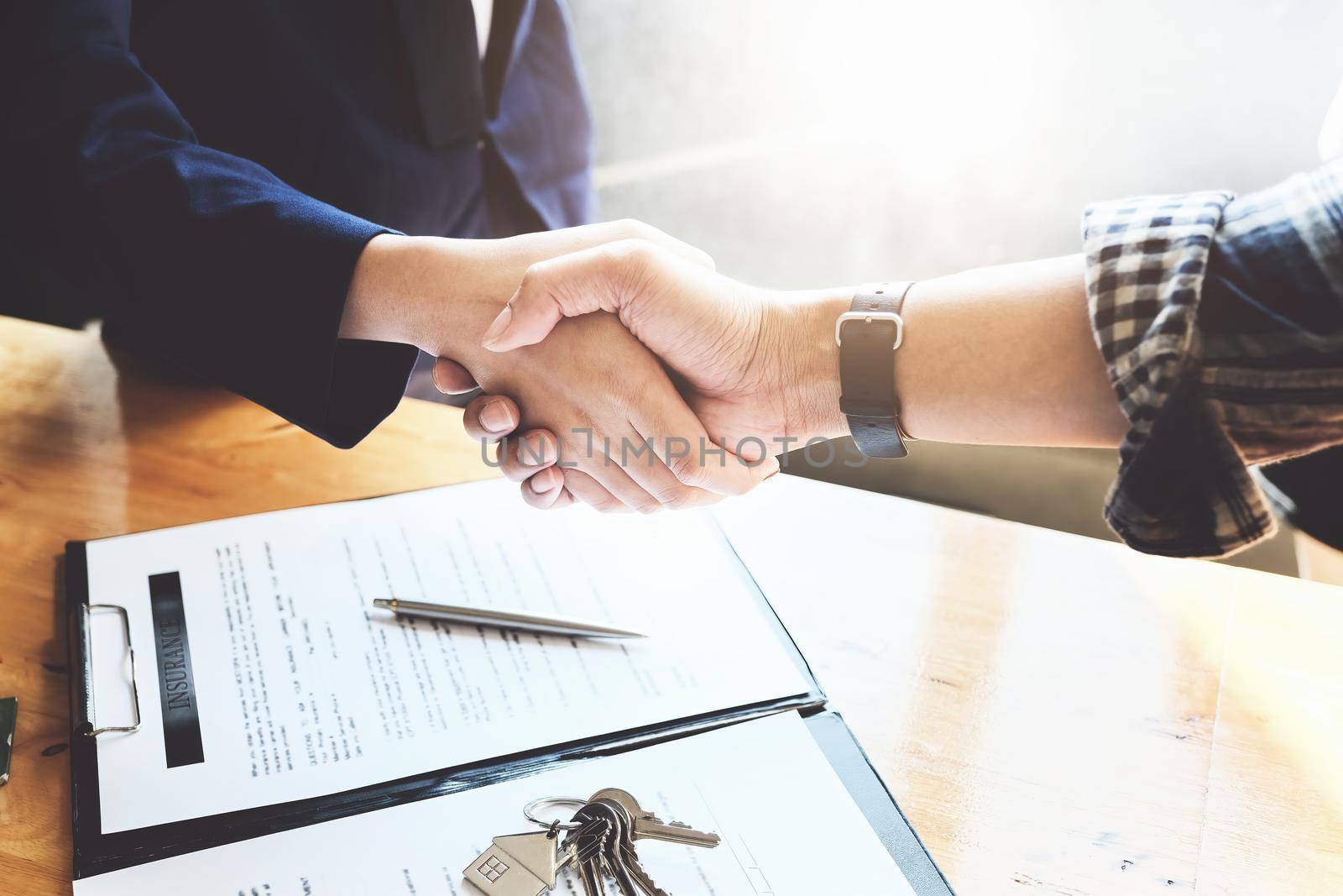 Focus on the congratulatory handshake. The real estate agent agrees to buy the home and hand the keys to the customer at the agent's office. conceptual agreement. by Manastrong