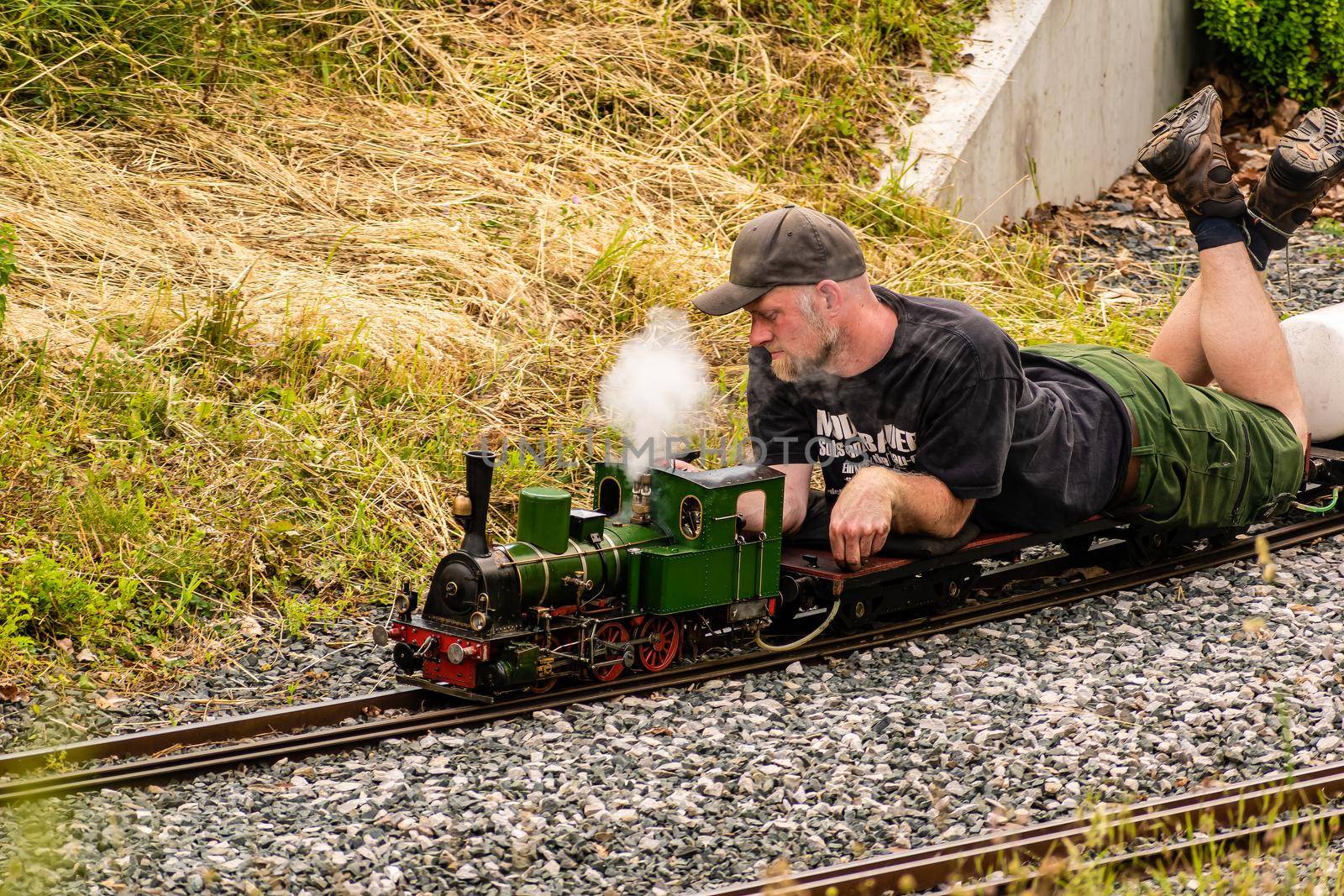 A man lying down drives a model of a steam locomotive by rostik924