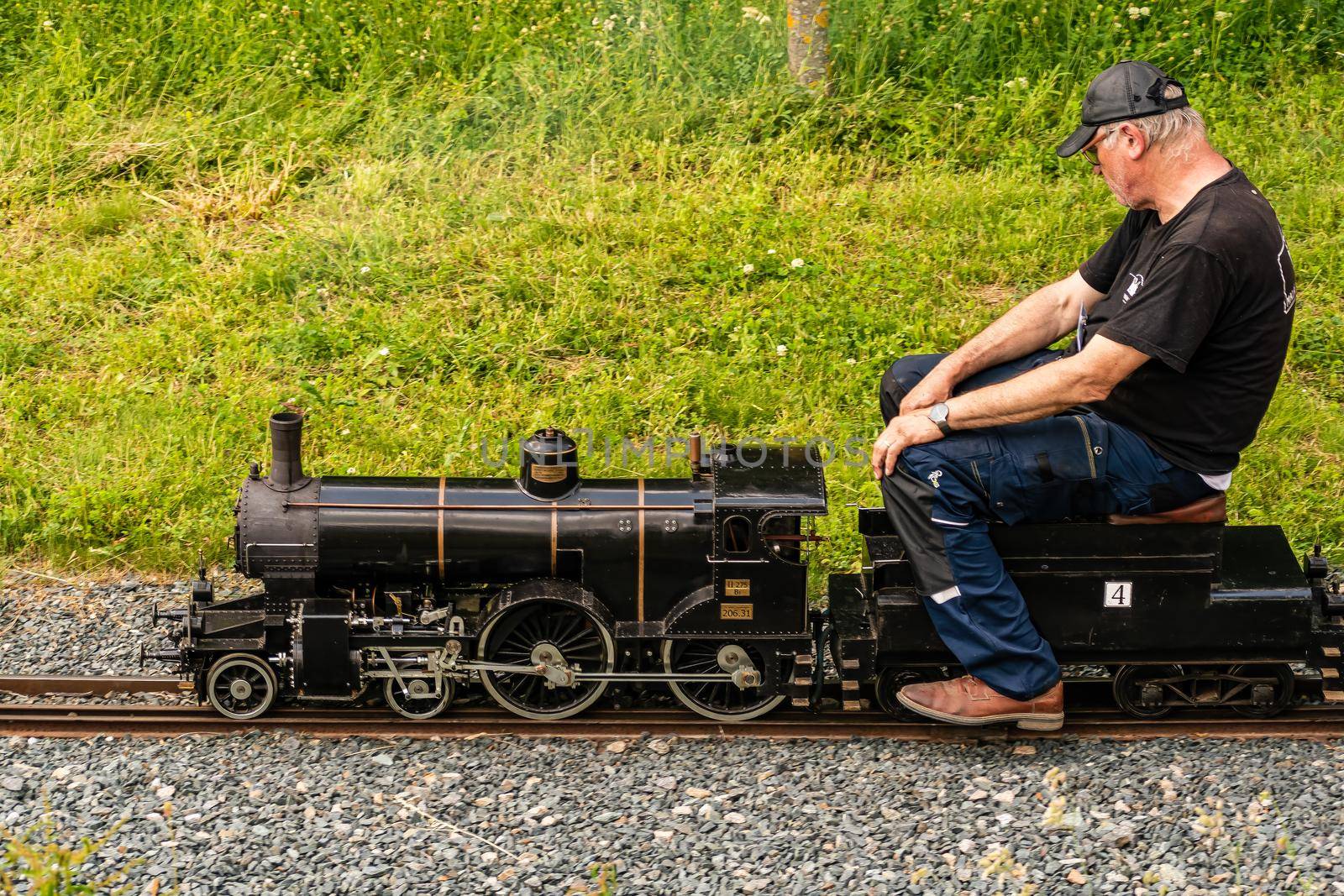 A seated man drives a large model of steam locomotive by rostik924