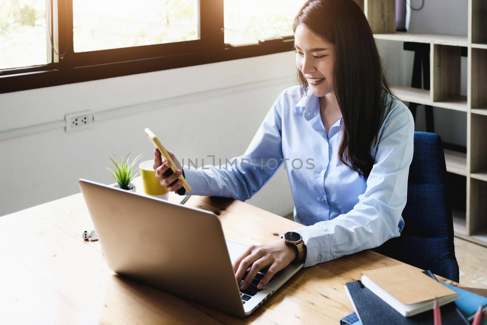 freelance concept, female hand holding smartphone and computers to design work as ordered by customers