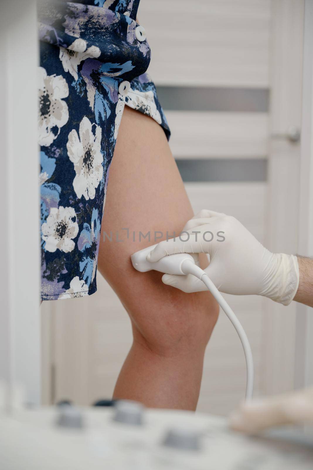 An orthopedic surgeon performs an ultrasound examination of the patient's leg veins in his office.Doctor ultrasound knee test. Scan medical equipment. Varicose ankle exam tool.